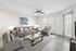 Modern living room with sleek gray sofas, stylish glass coffee table, and abundant natural light through large windows.