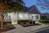 Charming residential entrance with well-lit pathway, lush greenery, and inviting covered porch at dusk.