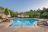 Inviting outdoor pool area with sleek lounge chairs and lush greenery at sunset.