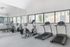 Bright and modern fitness center with cardio equipment, including treadmills and exercise bikes, set against large windows offering natural light and scenic views.
