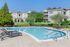 Inviting apartment complex with a sparkling swimming pool, surrounded by lush greenery and modern architecture.