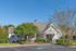Charming residence with a welcoming front porch and beautiful landscaped gardens under a clear blue sky.