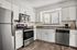 Modern kitchen with sleek stainless steel appliances, stylish countertops, and abundant natural light through a large window.