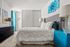 Bright, modern bedroom featuring a plush bed, vibrant turquoise accents, chic artwork, and elegant lighting.