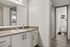 Bright and modern bathroom featuring sleek cabinetry, a spacious vanity with large mirror, and a pristine toilet area with stylish decor.