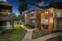 Charming apartment complex at dusk featuring a cozy pathway, lush greenery, and inviting balconies.