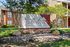 Charming Adair off Addison Apartment Homes entrance surrounded by lush greenery and stones.