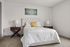 Elegant bedroom with a plush tufted headboard, modern bedside tables, and vibrant artwork accentuating the cozy ambiance.