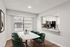 Bright and inviting dining area with a marble table and green chairs, seamlessly connecting to a modern kitchen featuring stainless steel appliances.
