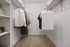 Luxurious walk-in closet with plush carpet and elegant shelving, featuring a variety of stylish clothing and accessories for a chic home ambiance.