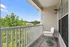 Charming balcony with a cozy chair, lush greenery, and clear blue skies for a perfect relaxing retreat.