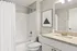 Modern bathroom design with elegant granite countertop, sleek fixtures, and stylish wall art above a pristine shower and bathtub.
