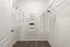 Spacious walk-in closet with neatly organized shelves and hanging space, featuring clean white shirts and stylish storage boxes.