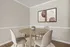 Modern dining area with a round wooden table, elegant beige chairs, and minimalist wall art in a bright, welcoming space.