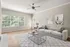 Bright and airy living room with large windows, elegant artwork, and a cozy sofa, perfect for relaxation.