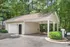 Charming detached garage with a covered carport surrounded by lush greenery, ideal for modern living.