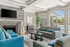 Elegant living room with striped sofas, cozy fireplace, modern decor, and large windows overlooking a poolside view.