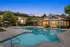 Inviting apartment complex with a luxurious swimming pool, surrounded by lush greenery and elegant architecture at sunset.