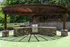 Charming outdoor grilling area with a stylish stone bar under a rustic wooden pergola, set against a lush green backdrop.
