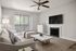 Chic and cozy living room with modern decor, featuring a plush sofa, marble coffee table, and a flat-screen TV, bathed in natural light from large sliding glass doors.