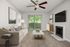 Elegant living room with plush beige sofa, textured carpet, stylish ceiling fan, and large sliding glass doors opening to greenery.