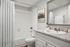 Elegant bathroom featuring a sleek granite countertop, modern fixtures, and a pristine white bathtub with a stylish shower curtain.
