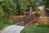 Charming apartment exterior with a scenic bridge, lush greenery, and inviting pathway leading to a welcoming entrance.