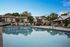 Inviting outdoor pool area in a serene apartment complex, featuring comfortable lounge chairs and lush greenery.