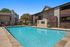 Inviting outdoor pool area with crystal clear water, surrounded by modern apartment buildings and lush greenery, perfect for relaxation and leisure.