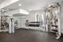 Modern fitness room with top-tier strength training equipment, dumbbells, and natural light through large windows.