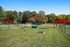 Inviting outdoor space with vibrant red umbrellas, lush greenery, and a pet-friendly play area for relaxation and recreation.
