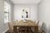 Elegant dining room with a rustic wooden table, six cozy chairs, and modern abstract art on the wall, featuring natural light from a large window.