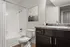 Bright and modern bathroom featuring pristine white tiles, elegant dark wood cabinetry, and stylish artwork.