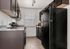 Modern kitchen featuring sleek dark cabinetry, bright natural light from a window, and polished countertops, perfect for culinary enthusiasts.