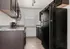 Chic modern kitchen featuring sleek dark cabinets, a large black refrigerator, and ample countertop space, illuminated by natural light through a large window.