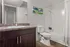 Modern bathroom with sleek dark wood cabinetry, elegant sink, wall art, and a pristine white shower and bathtub combo.