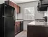 Modern kitchen with sleek black appliances, dark wood cabinetry, and ample natural light enhancing the contemporary design.
