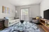 Bright and modern living room featuring a sleek sofa, stylish armchair, and glass coffee table with a beautiful view through sliding glass doors.