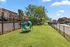 Vibrant outdoor space with a lush green lawn, play tunnel, and secure fencing, ideal for pet-friendly living.