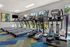 Modern fitness center with rows of sleek treadmills and elliptical machines, vibrant carpet, and large windows inviting natural light.