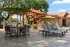 Inviting outdoor space featuring sun loungers, patio table with green umbrella, and a barbecue area under a charming wooden pergola, perfect for relaxing and entertaining.