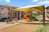 Charming apartment complex showcasing a vibrant children's playground with colorful slides and shaded canopy, surrounded by well-maintained residential buildings.