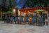 Inviting outdoor patio space featuring comfortable lounge chairs, elegant lighting, and green umbrellas surrounded by lush trees.