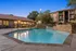 Charming apartment complex showcasing a serene pool area with elegant stone accents and inviting lounge chairs, perfect for relaxation.