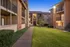 Charming apartment complex with spacious balconies, lush greenery, and inviting pathways.