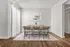Elegant dining room with a modern table set for six, featuring a minimalistic painting and natural light from vertical blinds.