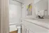 Modern bathroom with elegant white cabinetry, sleek counter, and stylish abstract artwork.
