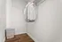 Spacious walk-in closet featuring elegant wooden flooring, hanging shirts, and a stylish wicker laundry basket.