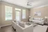 Elegant living room with modern decor, featuring cozy beige seating, a glass coffee table, large windows for ample natural light, and stylish wall art.