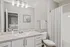 Elegant bathroom with marble countertop, modern fixtures, and a spacious mirror, reflecting a cozy bedroom.